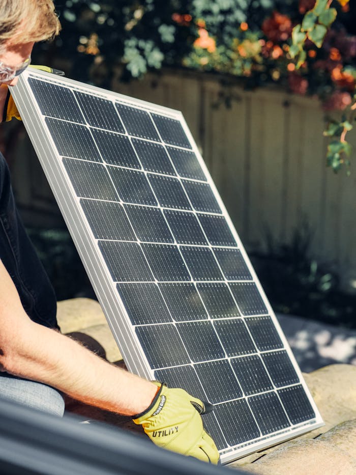 about-us A worker installs a solar panel in a garden, promoting clean energy.